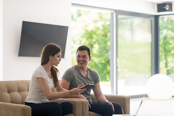 Image showing couple relaxing at  home with tablet and laptop computers