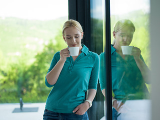 Image showing young woman drinking morning coffee by the window