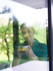 Image showing young woman drinking morning coffee by the window