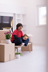 Image showing boy sitting on the table with cardboard boxes around him