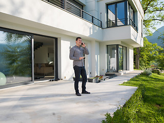 Image showing man using mobile phone in front of his luxury home villa