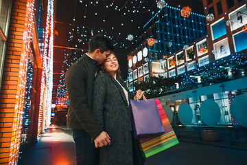 Image showing The happy couple with shopping bags enjoying night at city background