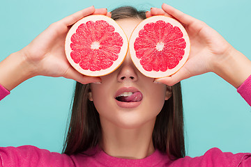 Image showing Pretty woman with delicious grapefruit in her arms.