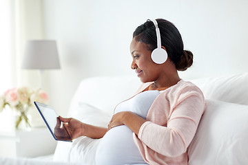 Image showing pregnant woman in headphones with tablet pc
