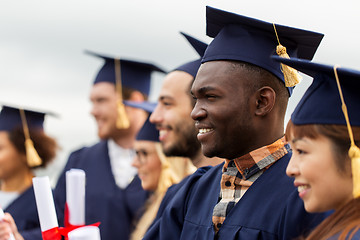 Image showing happy students in mortar boards with diplomas