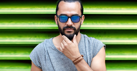 Image showing close up of man in sunglasses touching beard