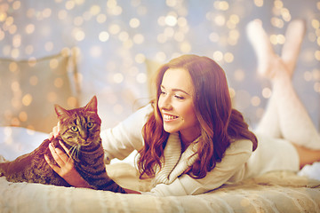 Image showing happy young woman with cat lying in bed at home