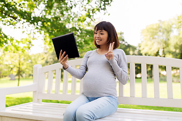 Image showing happy pregnant asian woman with tablet pc at park