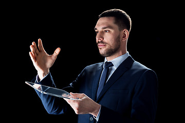 Image showing businessman in suit working with transparent tablet pc