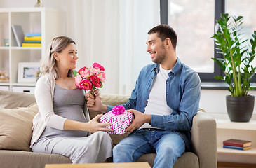 Image showing man giving flowers to pregnant woman at home