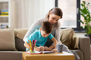 Image showing mother and son with workbook at home