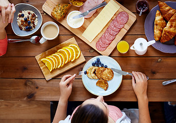 Image showing woman with food on table eating pancakes