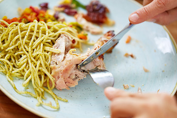 Image showing close up of hands eating chicken meat with pasta