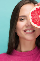 Image showing Pretty woman with delicious grapefruit in her arms.