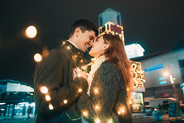 Image showing Young couple kissing and hugging outdoor in night street at christmas time