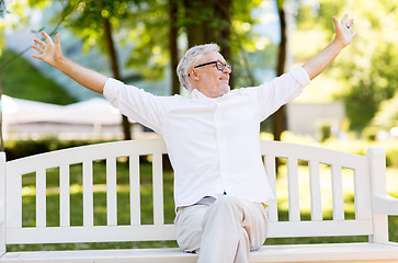 Image showing happy senior man sitting on bench at summer park