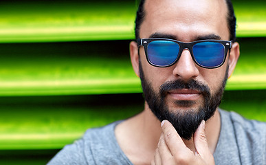 Image showing close up of man in sunglasses touching beard