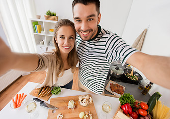 Image showing couple cooking food and taking selfie at kitchen