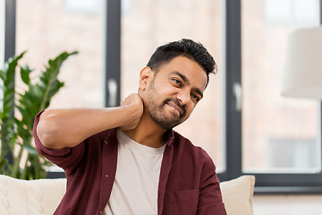 Image showing unhappy man suffering from neck pain at home