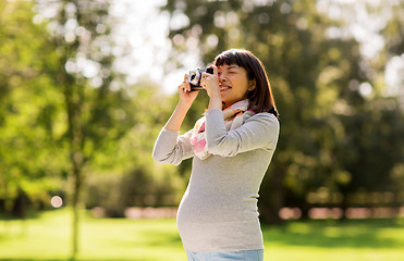 Image showing happy pregnant asian woman with camera at park