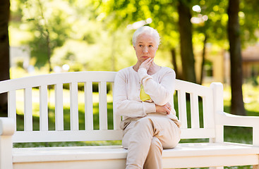 Image showing sad senior woman sitting on bench at summer park