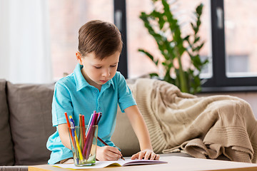 Image showing boy with notebook and pencils drawing at home