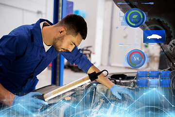 Image showing mechanic man with lamp repairing car at workshop