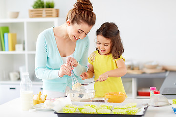 Image showing happy mother and daughter baking muffins at home