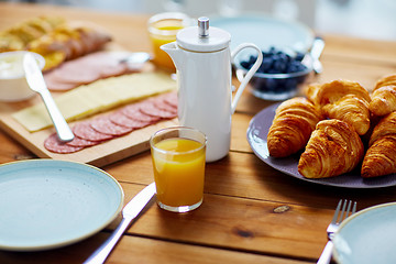 Image showing coffeepot and glass of juice on table at breakfast