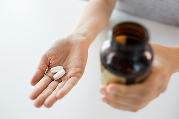 Image showing close up of hands holding medicine pills and jar