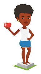 Image showing Woman standing on scale and holding apple in hand.