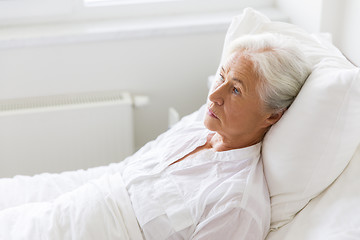 Image showing sad senior woman lying on bed at hospital ward