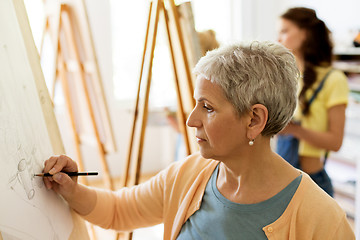 Image showing senior woman drawing on easel at art school studio