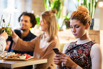 Image showing woman with smartphone and friends at restaurant