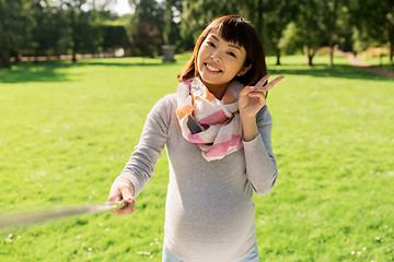 Image showing happy pregnant asian woman taking selfie at park