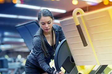 Image showing young woman adjusting leg press machine in gym