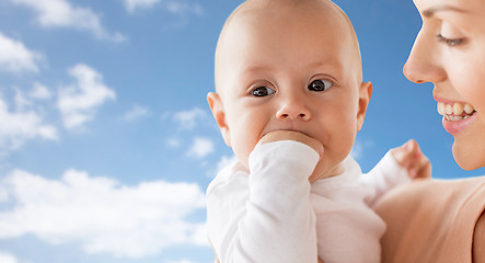 Image showing happy mother with baby sucking fingers over sky