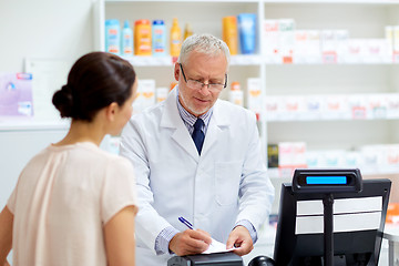 Image showing senior apothecary with prescription at pharmacy