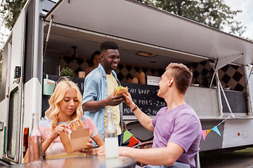 Image showing happy friends with drinks eating at food truck