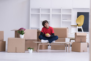 Image showing boy sitting on the table with cardboard boxes around him