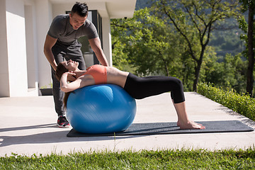 Image showing woman and personal trainer doing exercise with pilates ball