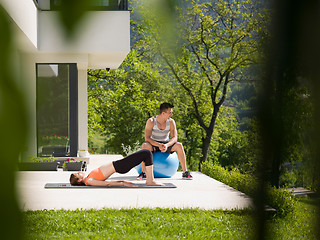 Image showing woman and personal trainer doing exercise with pilates ball