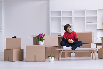 Image showing boy sitting on the table with cardboard boxes around him