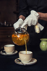 Image showing Pouring tea with sea buckthorn