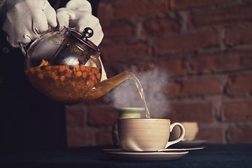 Image showing Pouring tea with sea buckthorn