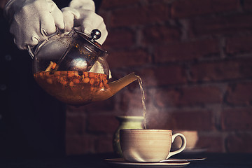 Image showing Pouring tea with sea buckthorn