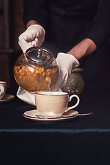 Image showing Pouring tea with sea buckthorn