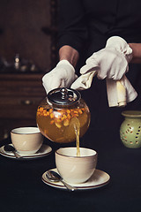 Image showing Pouring tea with sea buckthorn