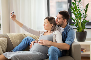 Image showing man and pregnant woman taking selfie at home