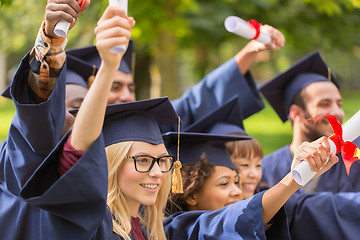 Image showing happy students in mortar boards with diplomas